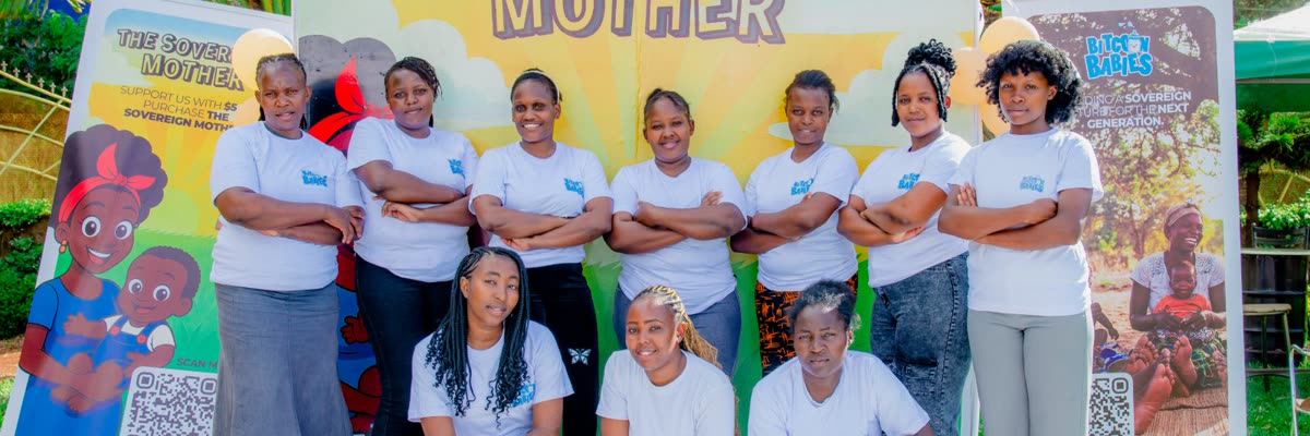 The Bitcoin Babies team and mothers posing in front of The Sovereign Mother campaign banner