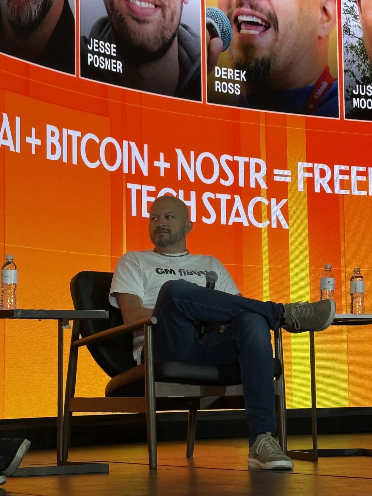 Derek Ross on the Genesis Stage at Bitcoin 2026 in front of an 'AI + Bitcoin + Nostr = Freedom Tech Stack' panel banner